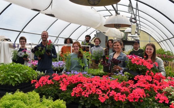 a group of people standing behind a table of poinsettias smiling at the camera